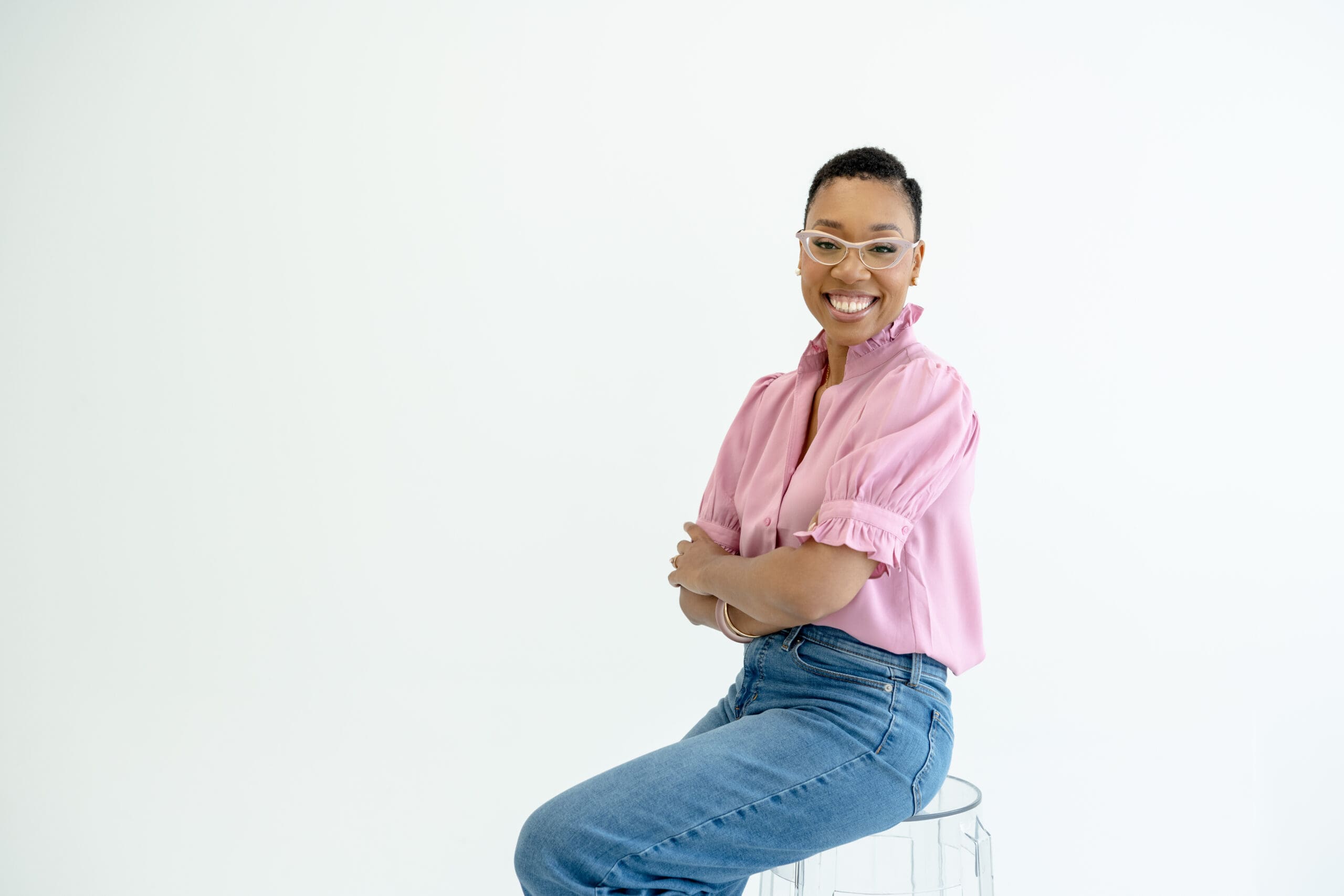 Chelsea Quenum, Northern Virginia wedding planner, smiling in a pink blouse against a bright white background.