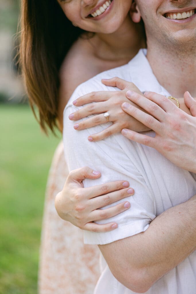 Close-up of a newly engaged couple embracing, highlighting an oval engagement ring on the bride-to-be’s hand in Northern Virginia.