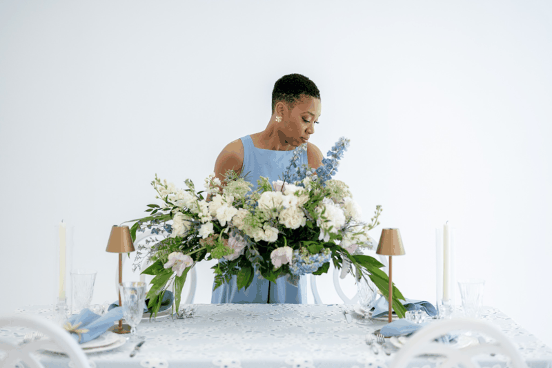 Chelsea Quenum styling a floral centerpiece during a wedding design shoot, demonstrating attention to detail and floral placement.