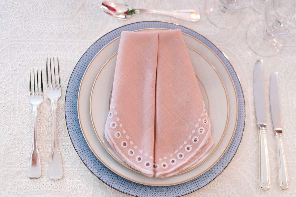 Bright pink and red florals, embroidered linens, and glassware from a Modern Parisian wedding editorial at Swann House, designed by Chelsea Quenum Wedding Planning & Event Design.