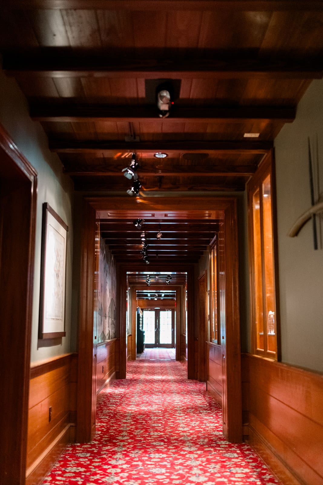 Warm wood-paneled hallway at Clyde’s Willow Creek Farm with a patterned red carpet and soft ambient lighting.