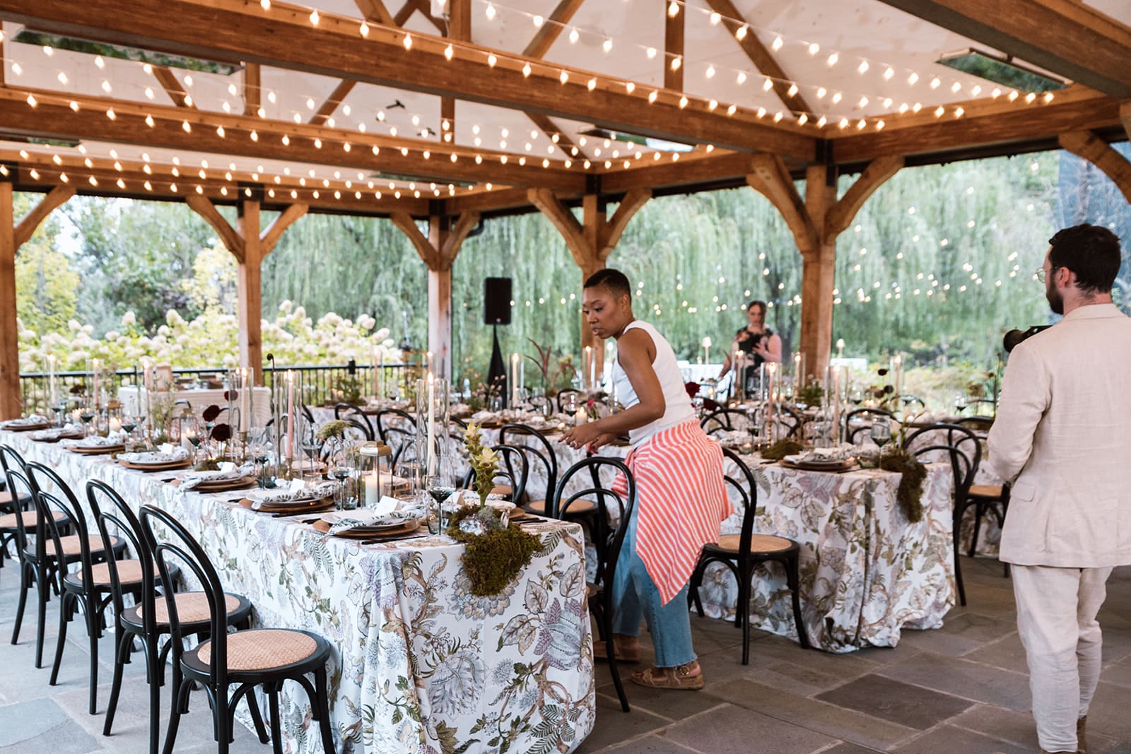 Wedding planner Chelsea Quenum adjusting place settings during setup for a modern barn-style dinner at Clyde’s Willow Creek Farm.