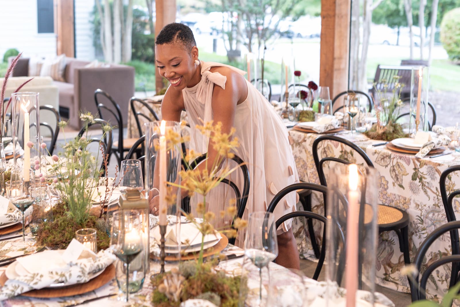 Chelsea Quenum, wedding planner and designer adjusting place settings during reception setup.