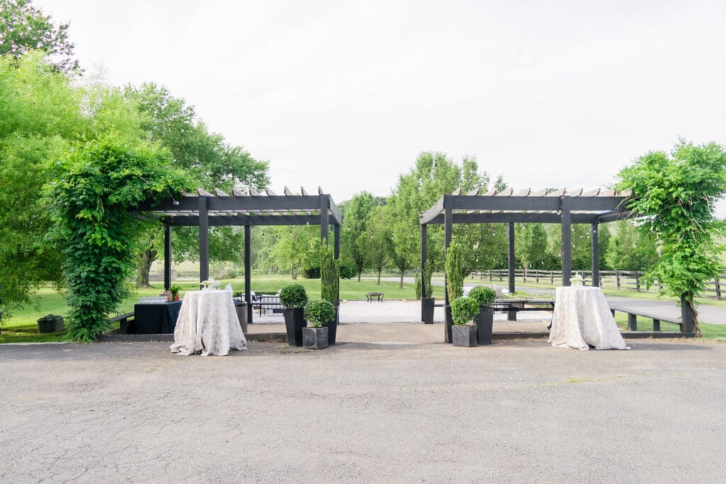 Outdoor cocktail hour space with pergolas and linen-covered high-top tables at a Northern Virginia wedding venue