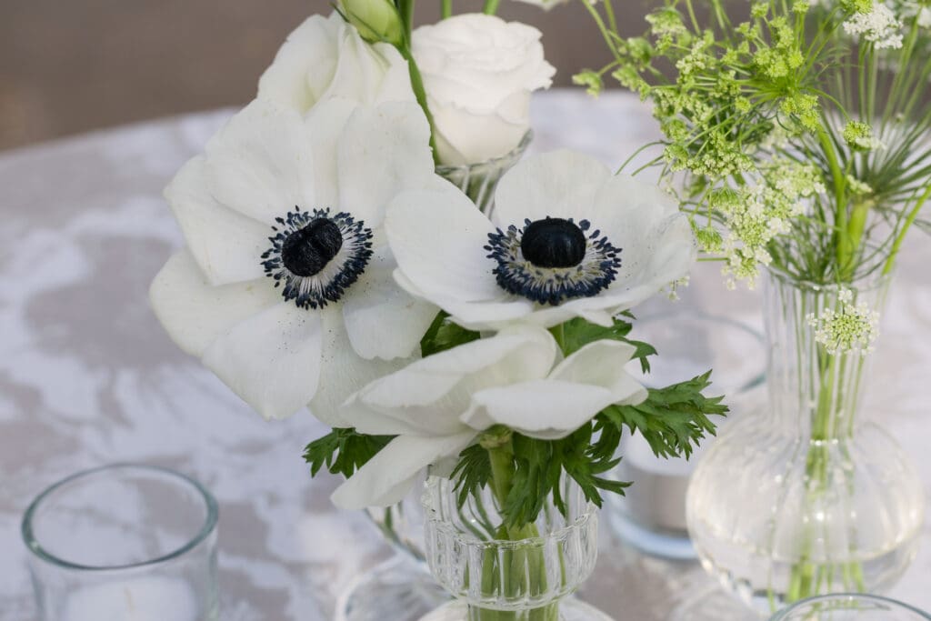 White floral centerpiece with anemones and bud vases on a wedding reception table in Northern Virginia