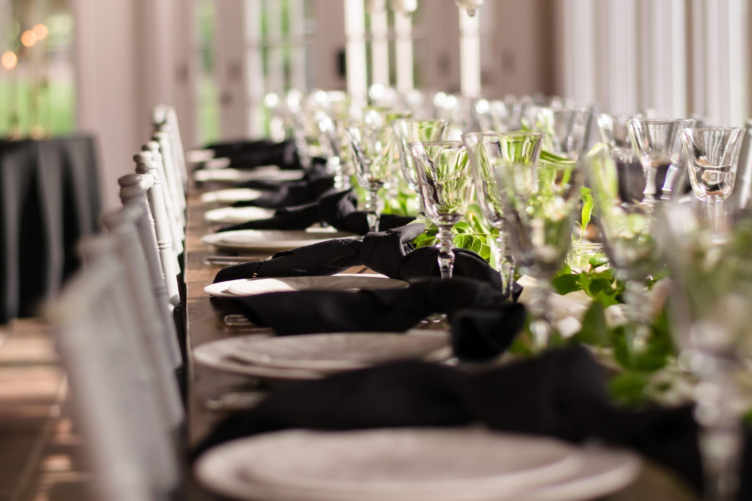 Long reception table with black napkins, white chairs, candlelight, and greenery at a Northern Virginia wedding