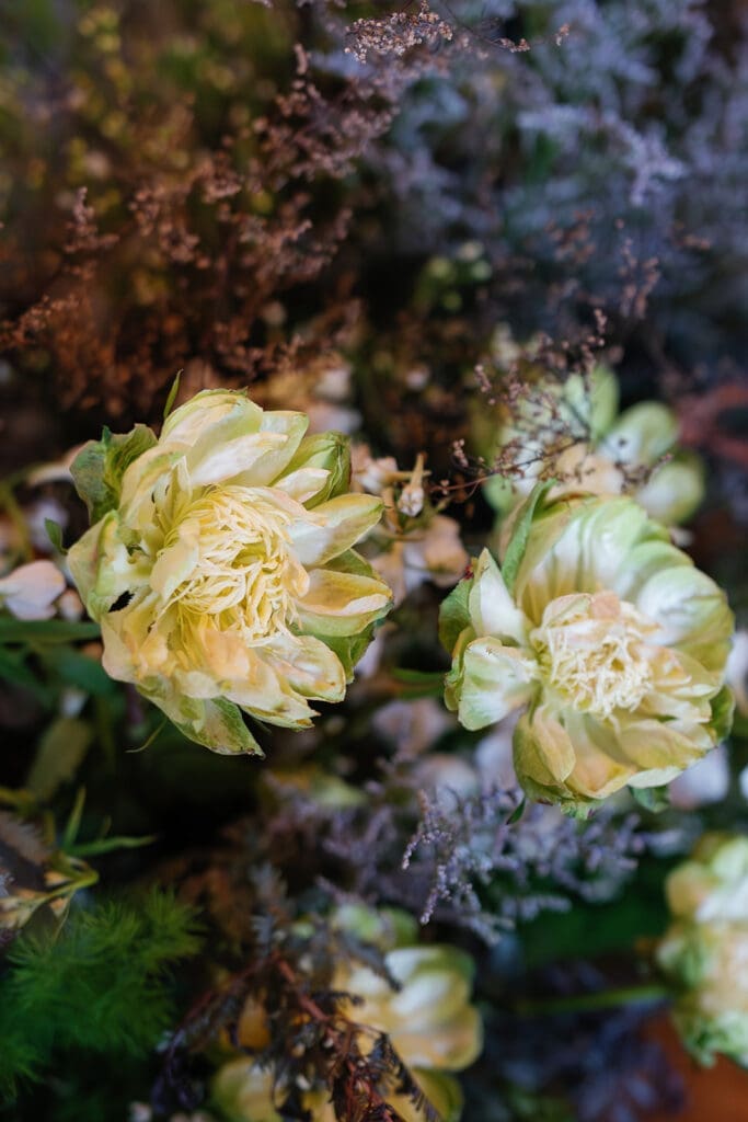 Close-up of soft cream flowers and layered greenery arranged in an organic floral design at The Manor 1858.