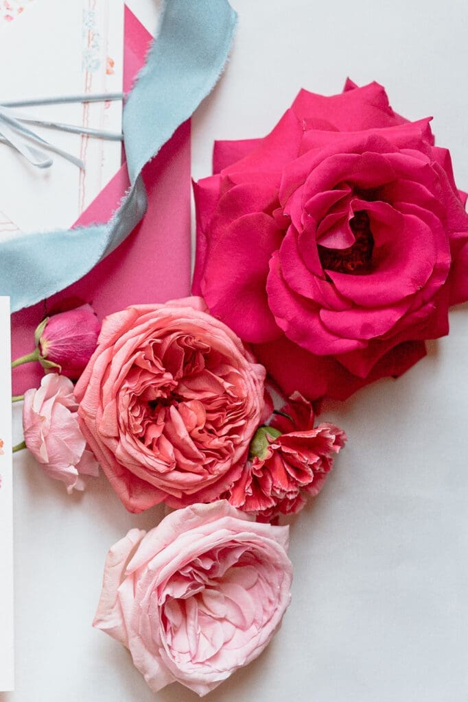 Pink and red wedding florals with blue silk ribbon and layered stationery details from a colorful Swann House wedding editorial.