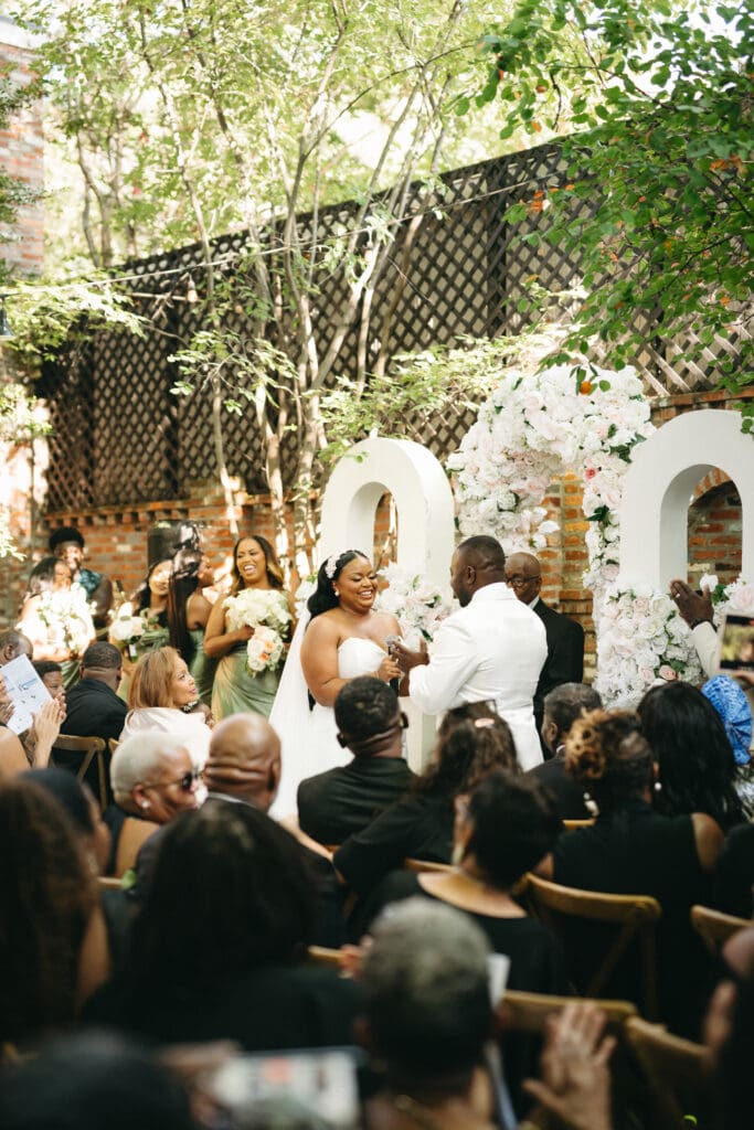 Outdoor wedding ceremony at Fathom Gallery Georgetown with the couple exchanging vows beneath a white floral installation in the courtyard.