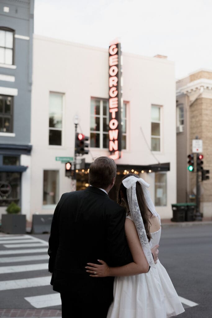 Newlywed couple standing on a Georgetown street in front of the glowing Georgetown Theater sign after their wedding celebration.